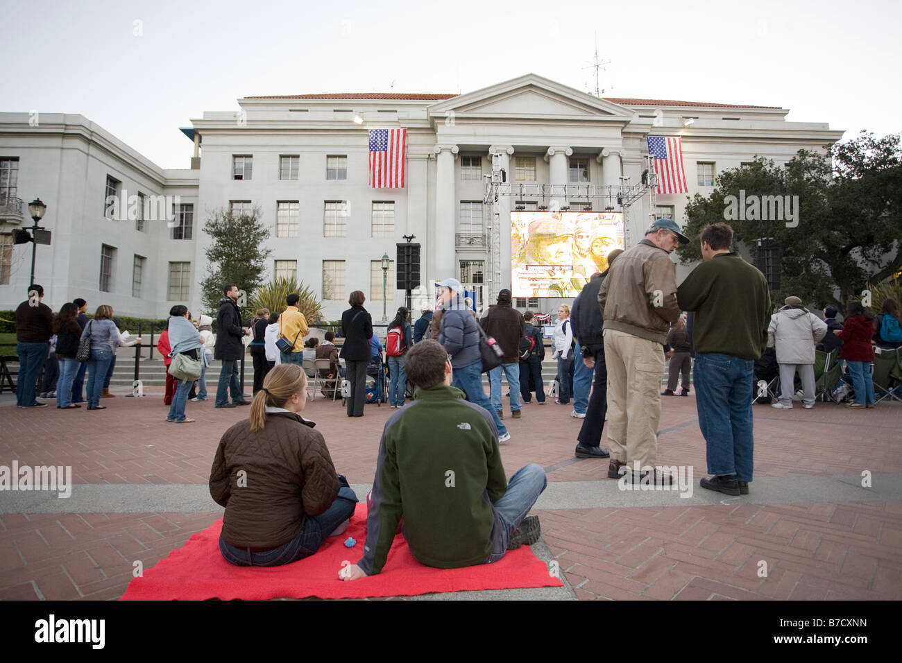 Un couple s'asseoir sur une couverture à l'attente de voir l'investiture de Barack Obama sur le jumbotron à UC Berkeley. Banque D'Images