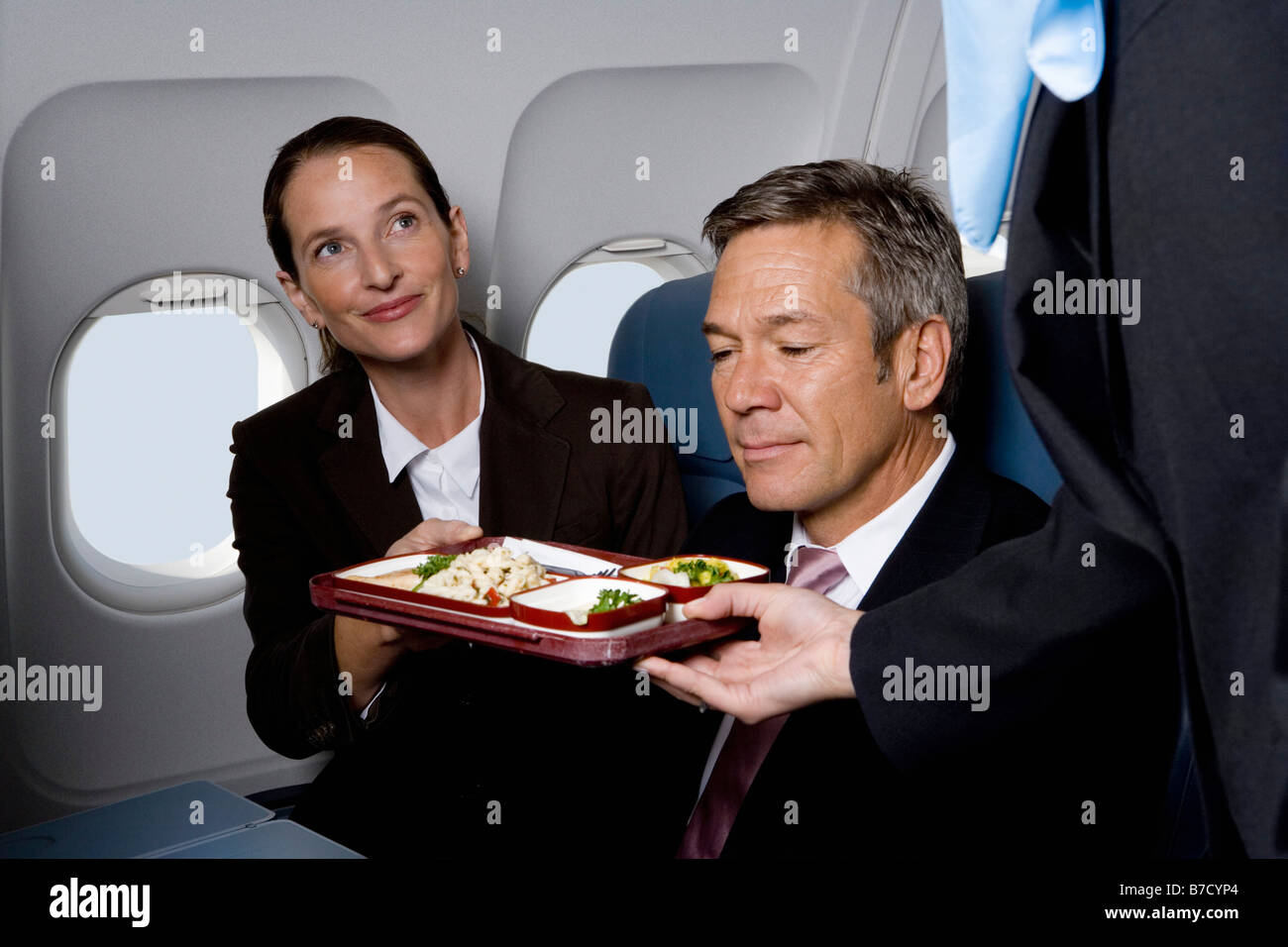 Les gens d'affaires dans un avion d'être servi de la nourriture de la compagnie aérienne Banque D'Images