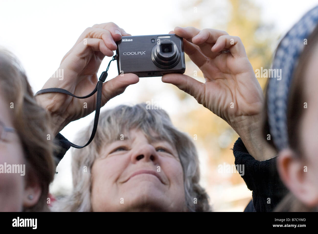Une femme plus âgée prend une photo avec un appareil photo compact à l'événement d'inauguration à l'Université de Californie, Berkeley. Banque D'Images