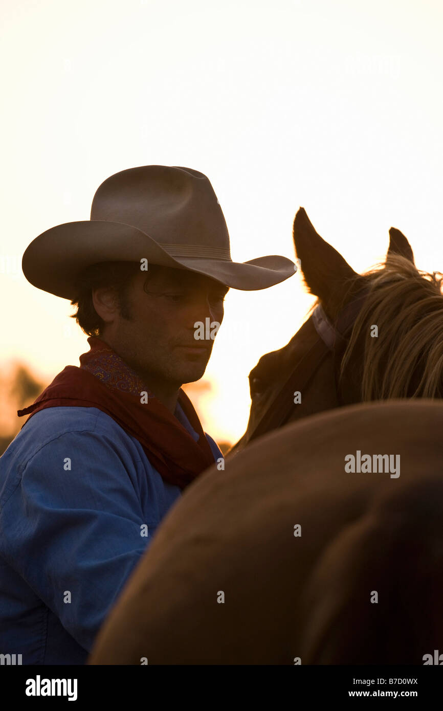 Un cowboy debout à côté de son cheval Banque D'Images