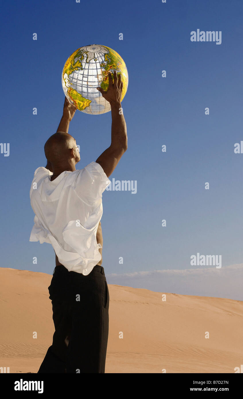 Un homme tenant un globe gonflable dans le désert Banque D'Images