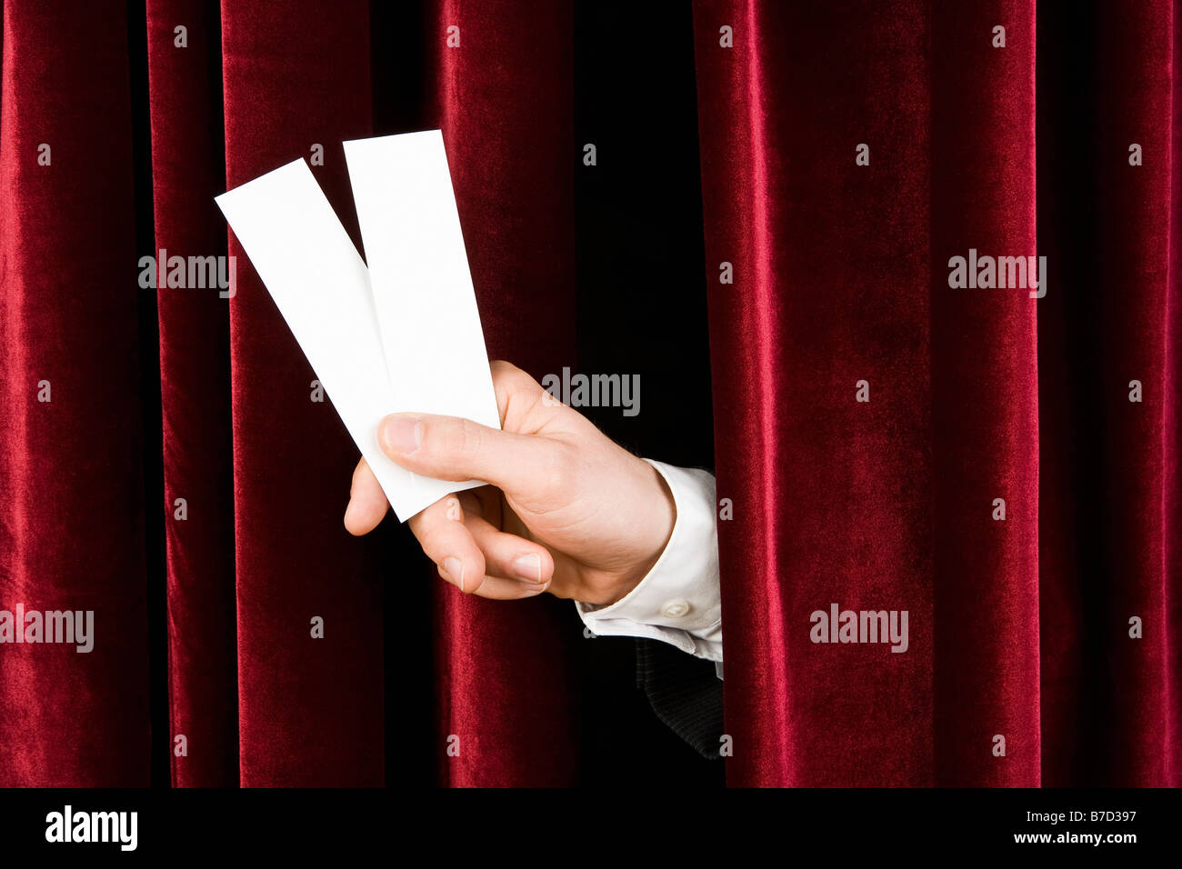 Une main tenant deux billets par l'intermédiaire d'un rideau de velours rouge Banque D'Images