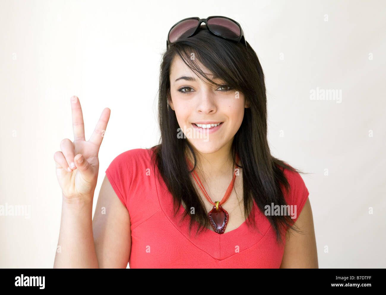 Une jeune fille avec des lunettes sur la tête donnant un signe V Photo  Stock - Alamy