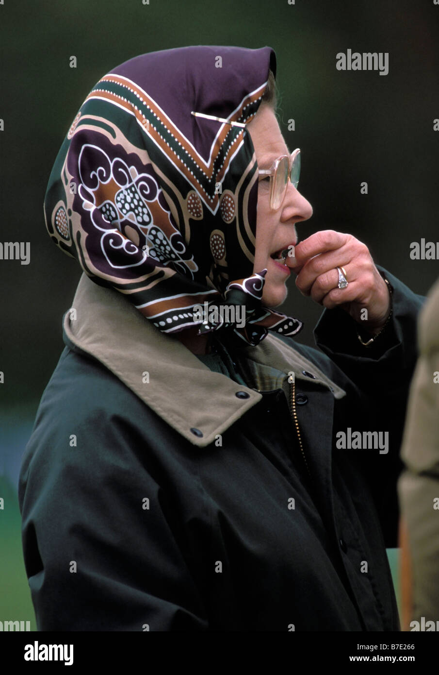 La reine Elizabeth II, portant des lunettes, un foulard et une veste cirée verte. Piquant le doigt et regardant anxieux. Le Royal Windsor Horse Show, 1989 Banque D'Images