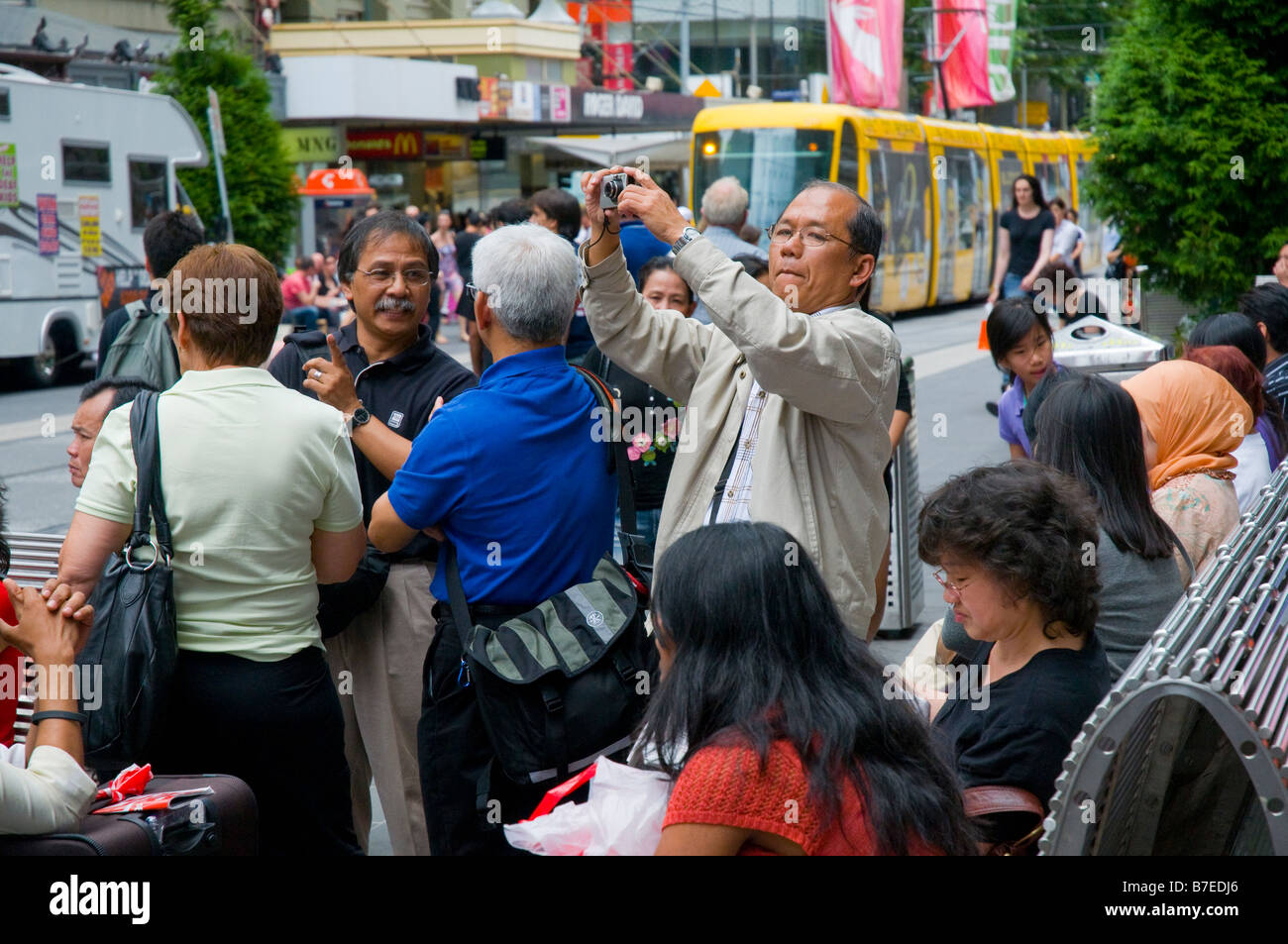 Un touriste asiatique de la prise de vue à un arrêt de tram avec un appareil photo numérique dans une rue Bourke Melbourne Banque D'Images