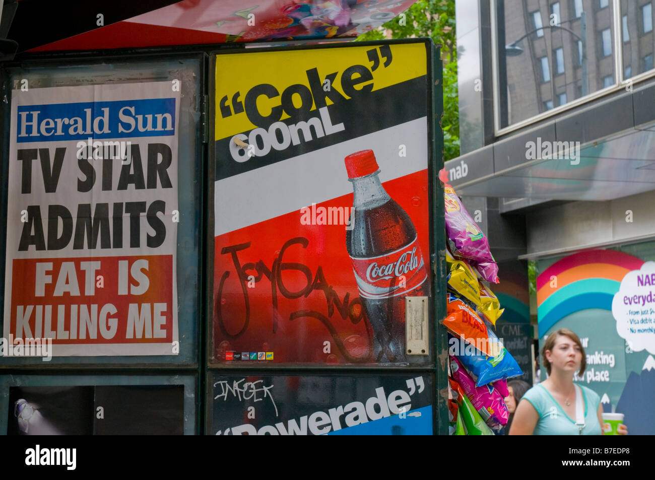 Titre d'affiche pour le tabloïd Herald Sun journal à Melbourne Victoria Australie juxtaposé à côté d'une affiche de boisson gazeuse Coco Cola Banque D'Images