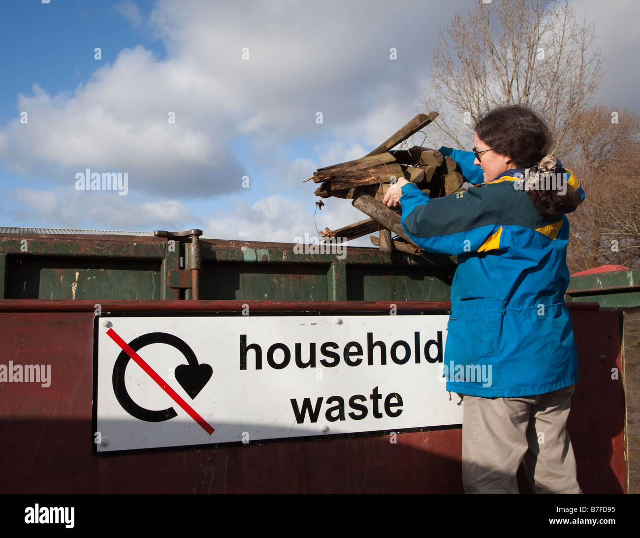 Femme jetant du bois pourri des ordures ménagères aller au chantier de recyclage Wales UK Banque D'Images