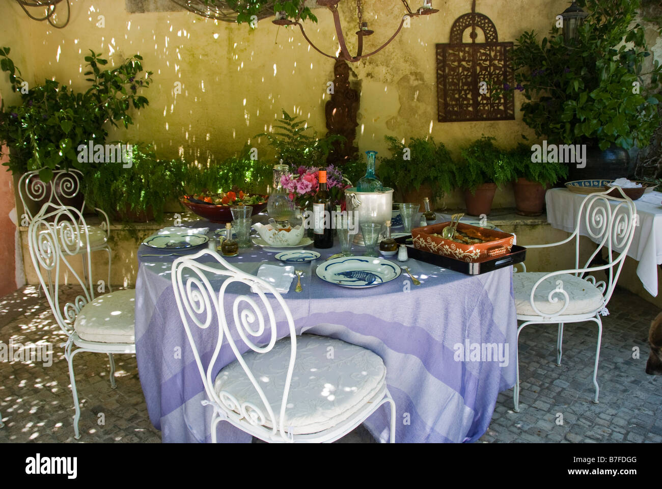 L'été au Portugal. Une table pour le déjeuner à l'extérieur, à l'ombre d'une énorme wistérie Banque D'Images