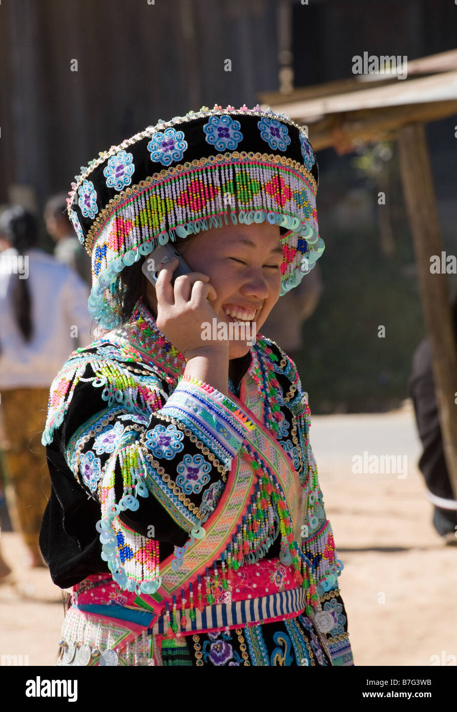 Une jeune femme Hmong en costume traditionnel des pourparlers sur un téléphone mobile pendant une cérémonie du Nouvel An Hmong. Banque D'Images