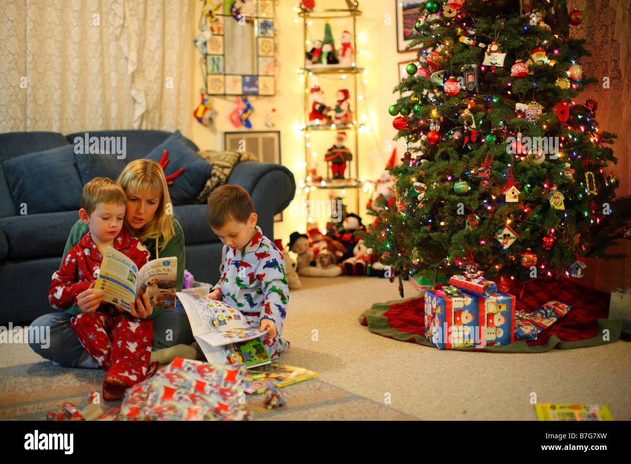 Mère la lecture de livres aux enfants par l'arbre de Noël Banque D'Images