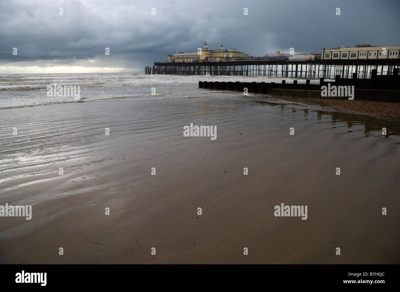 Marée montante sur la plage de sable sur la côte du Sussex avec Hastings pier dans l'arrière-plan Banque D'Images
