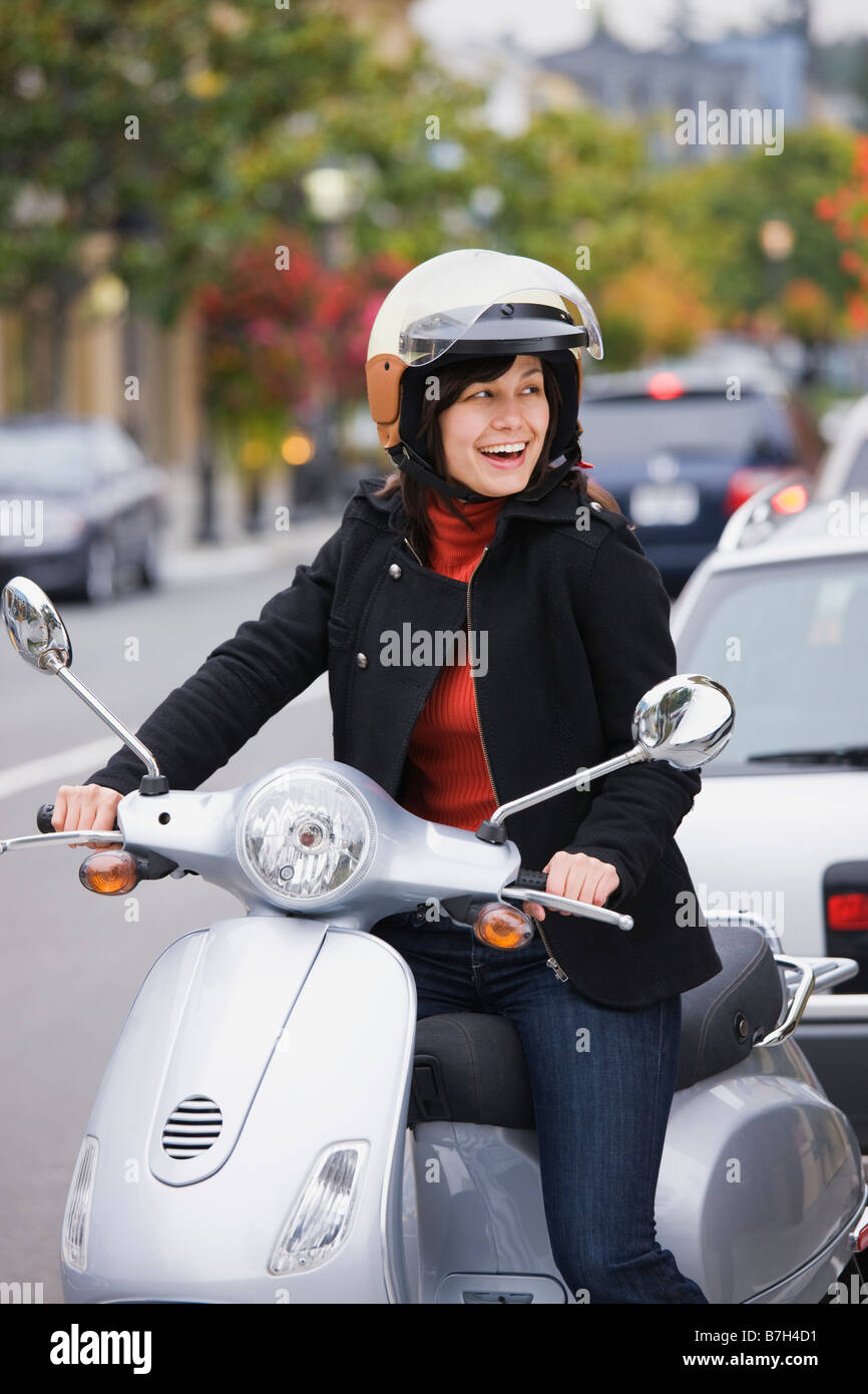 Mixed Race woman in casque scooter conduite Banque D'Images