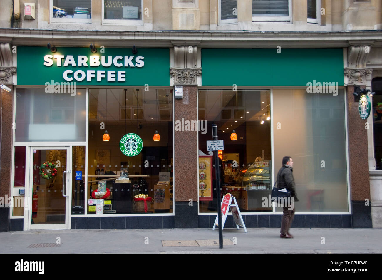Homme marchant passé Starbucks, Londres Banque D'Images