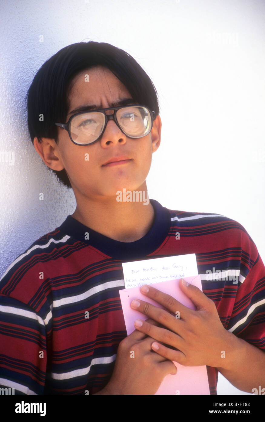 Korean teen boy reflète sur une triste nouvelle qu'il vient de lire dans la lettre. Banque D'Images