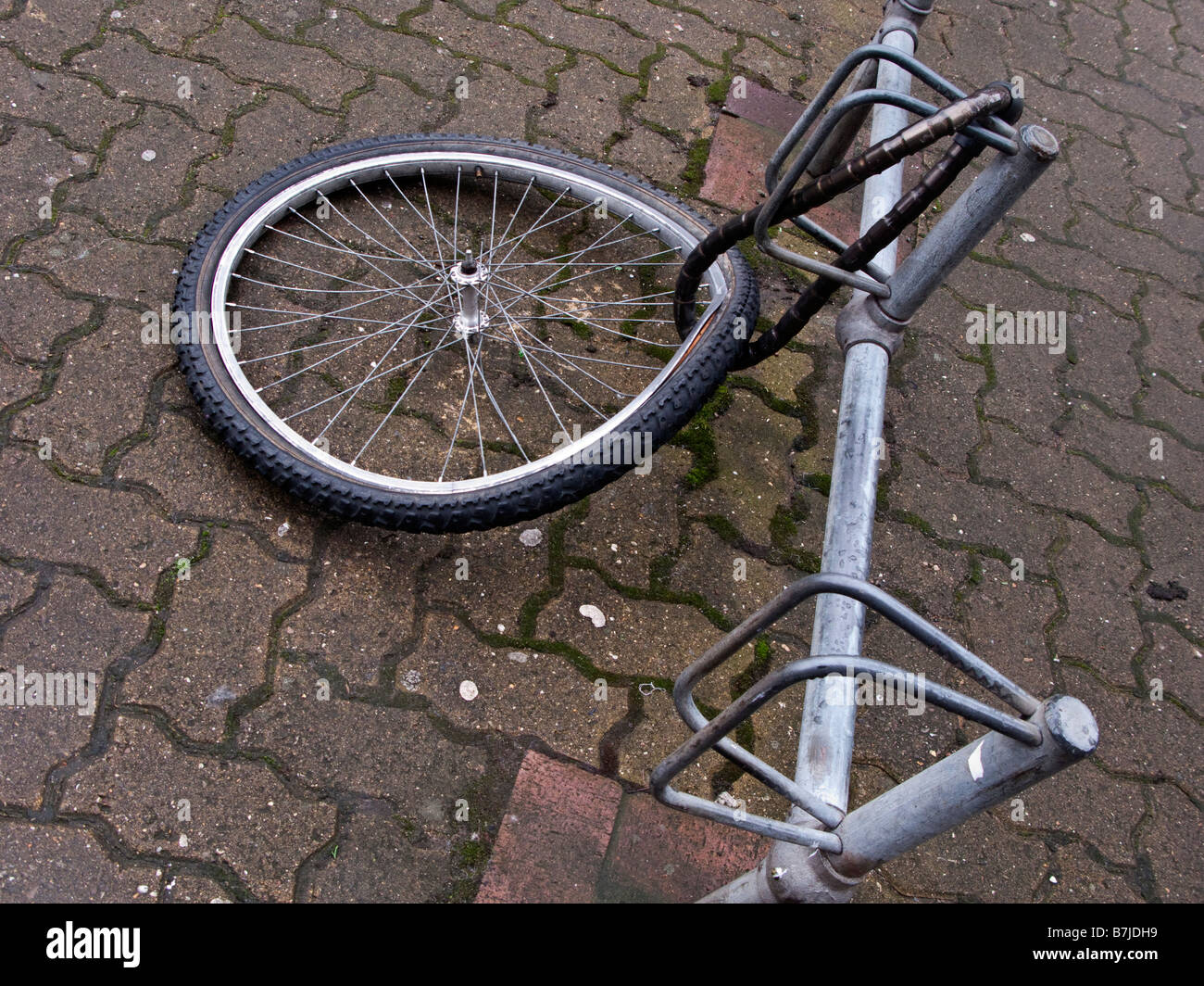 Une roue de vélo endommagé est tout ce qui reste d'un vélo enchaîné à un bike stand Banque D'Images