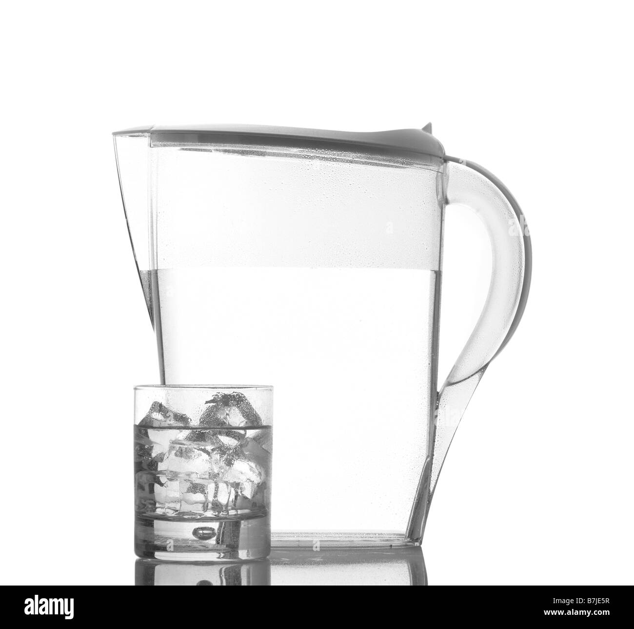 Pichet en verre avec des glaçons et d'eau minérale réfléchi sur fond blanc Banque D'Images