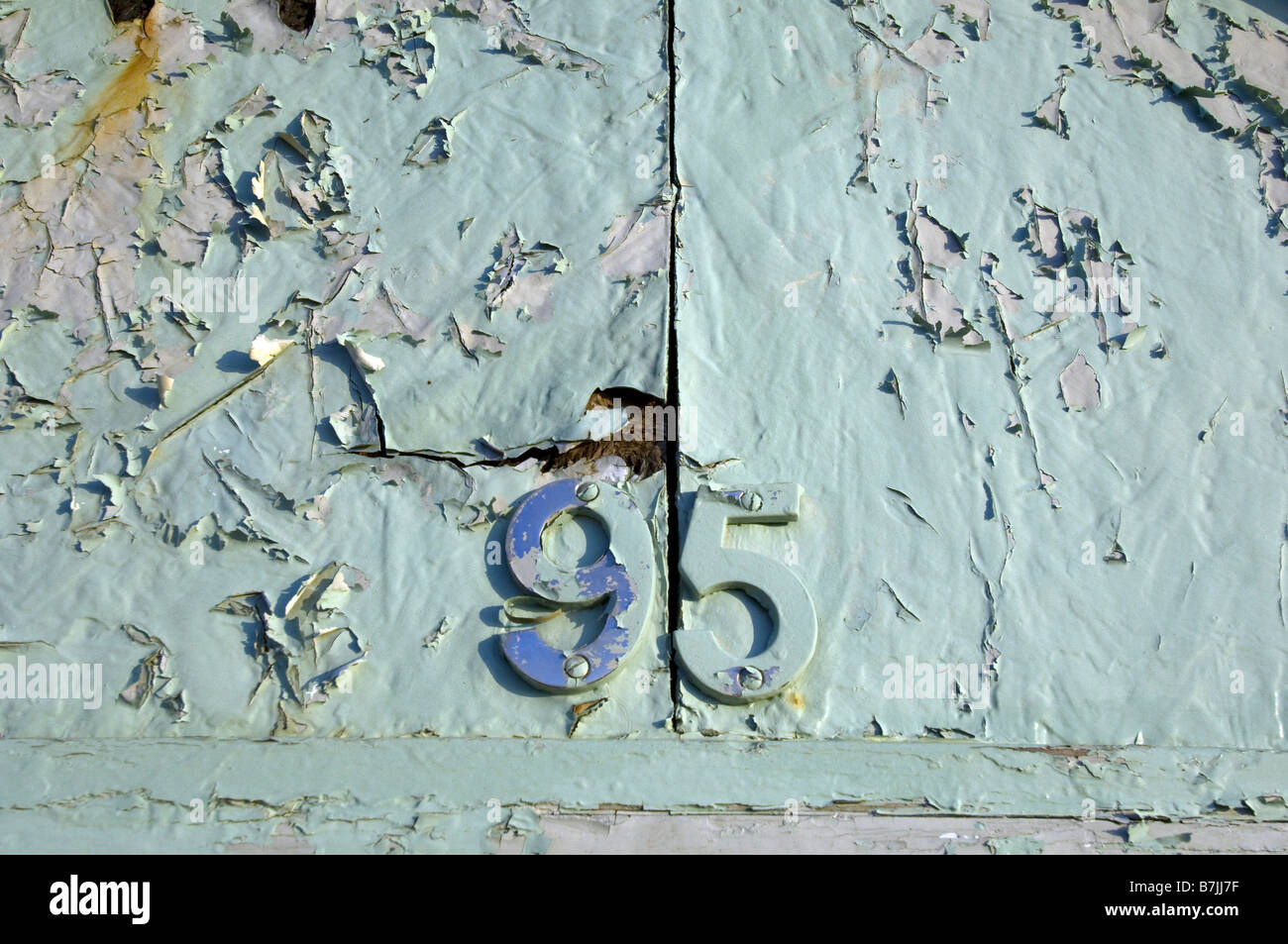 L'écaillage de la peinture verte en plastique bleu recouvrant le numéro 95 sur un front de plage sur la promenade de Hove Banque D'Images