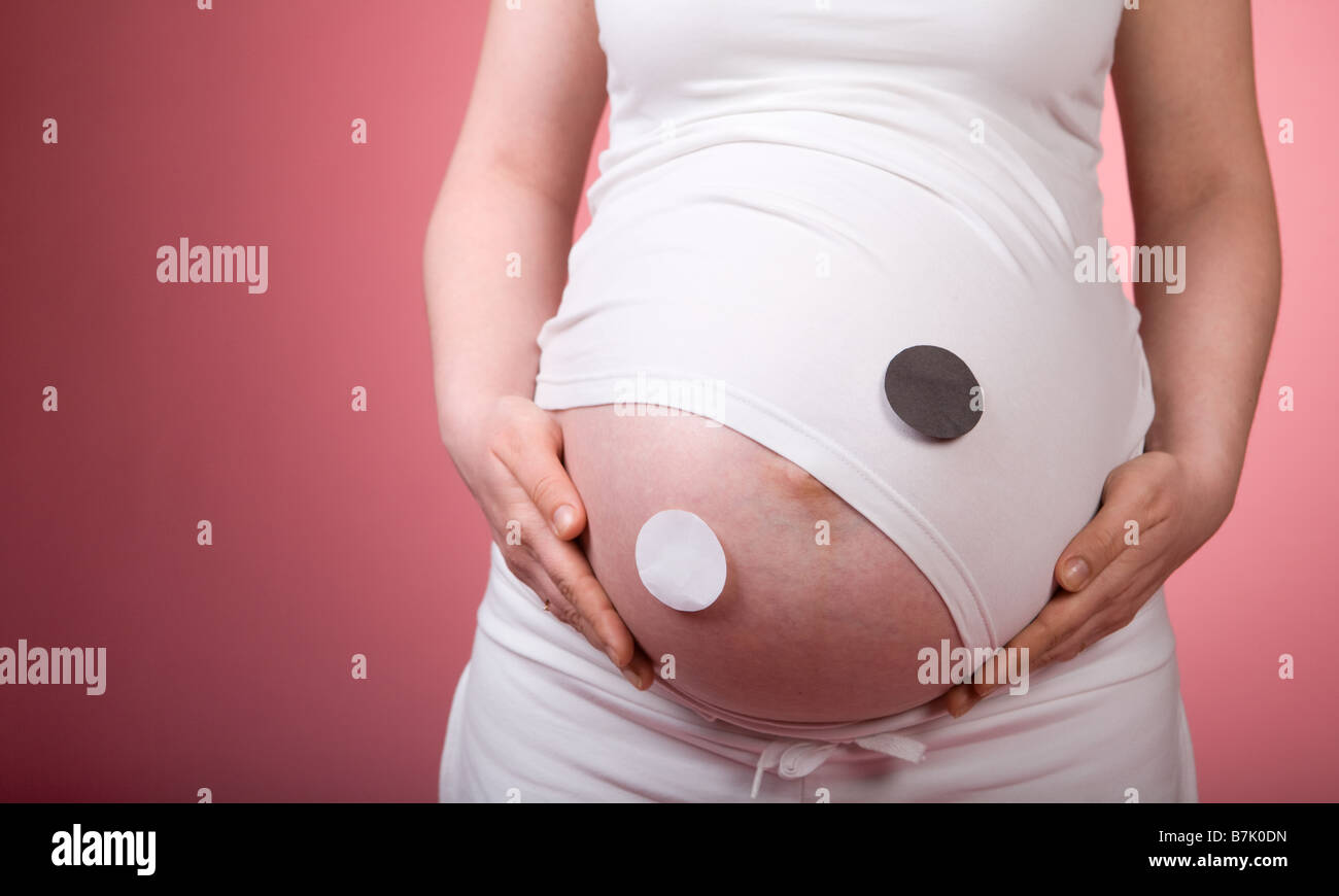 Le symbole Yin Yang sur 33 semaines de grossesse le ventre. Studio shot sur fond rose Banque D'Images