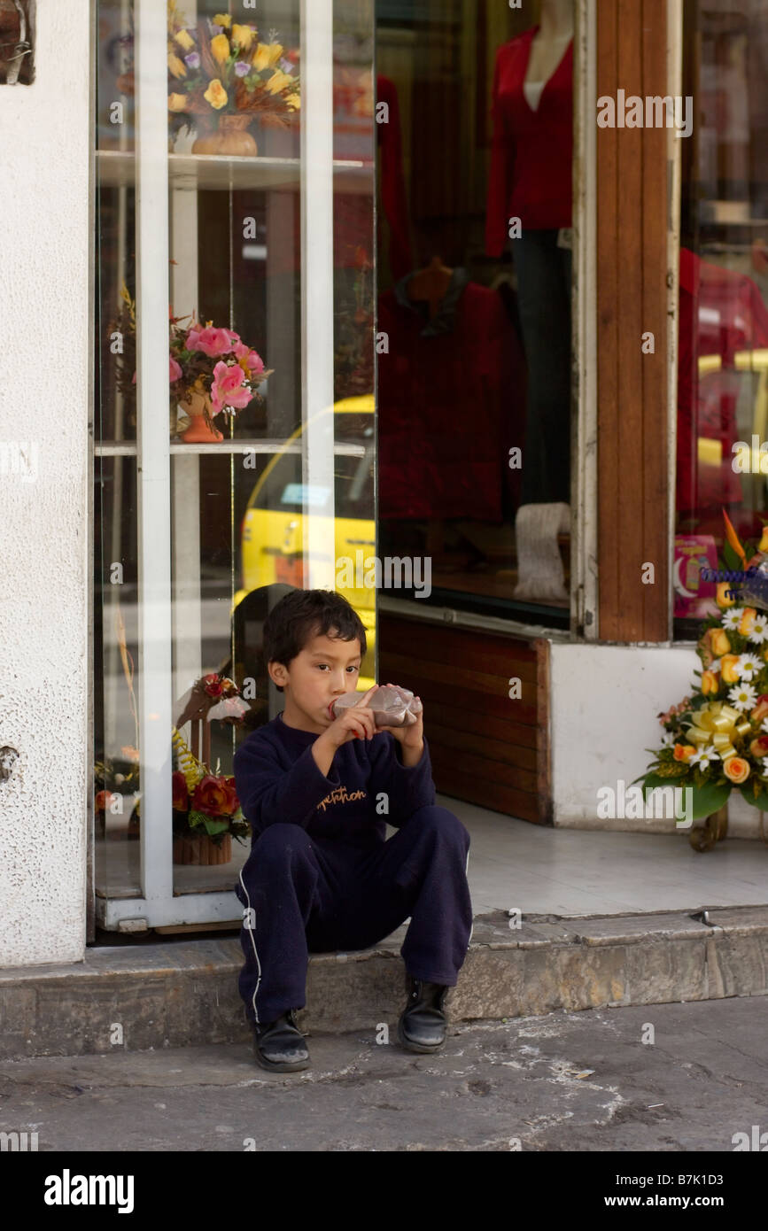 Garçon assis en face d'une boutique d'Ambato Equateur Banque D'Images