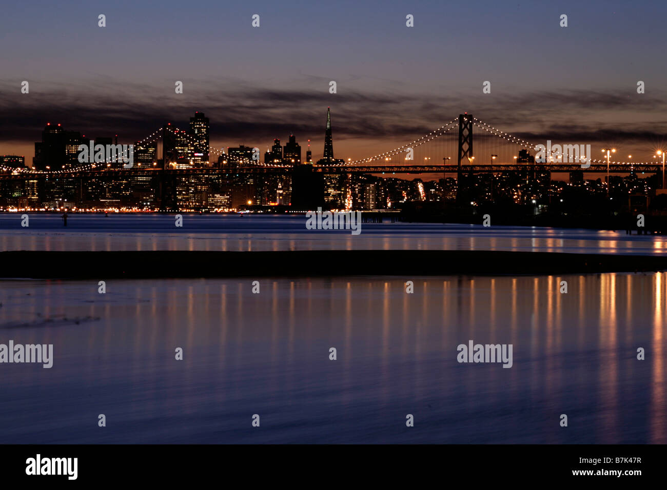 Horizon de San Francisco, la Transamerica Building et Bay Bridge au crépuscule de nuit avec les lumières reflètent dans l'eau Banque D'Images