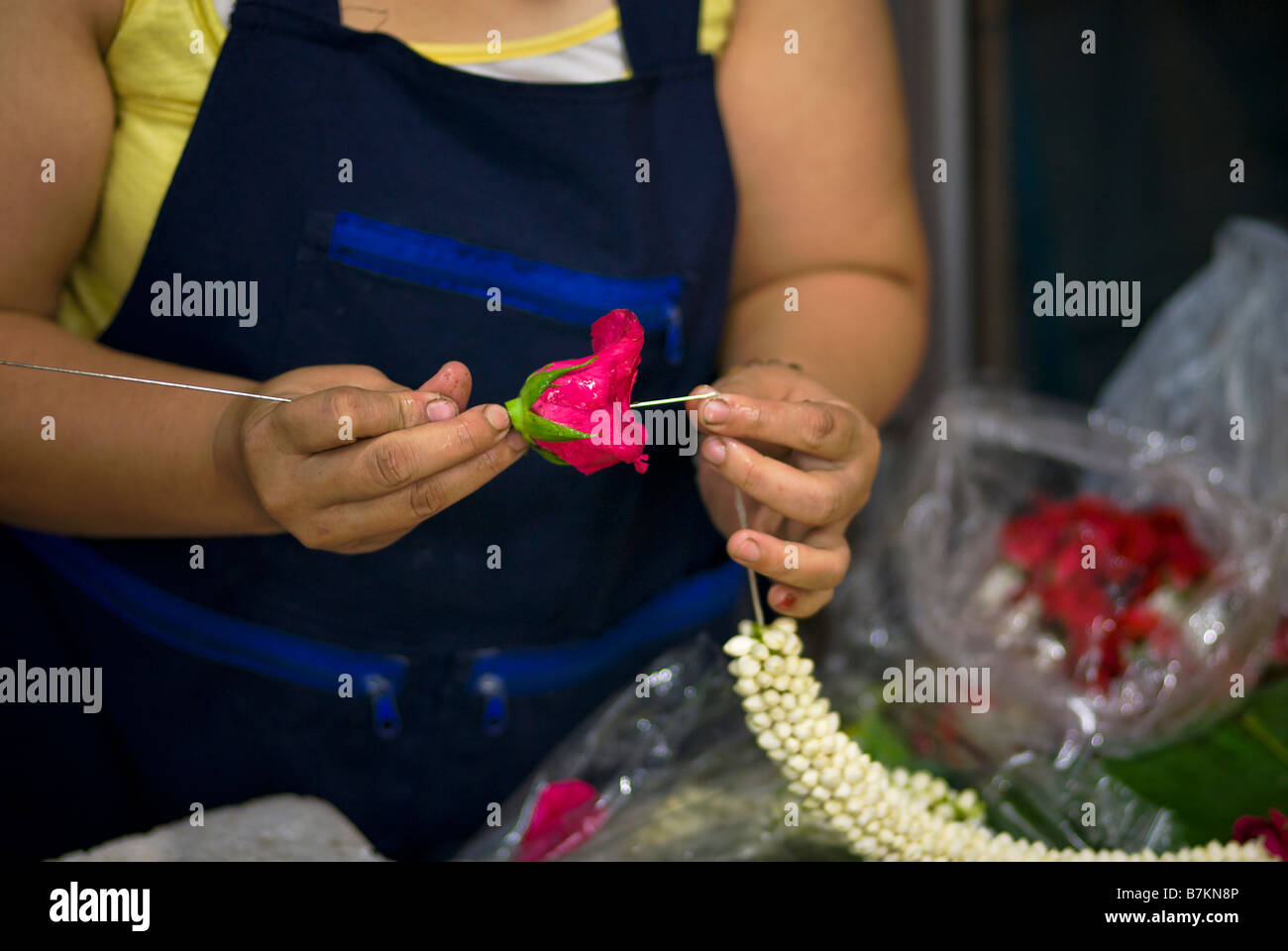 Détail de la femme faisant des offrandes de fleurs de dévotion sur un étal au marché aux fleurs de Pak Khlong Talad Bangkok Thaïlande Banque D'Images
