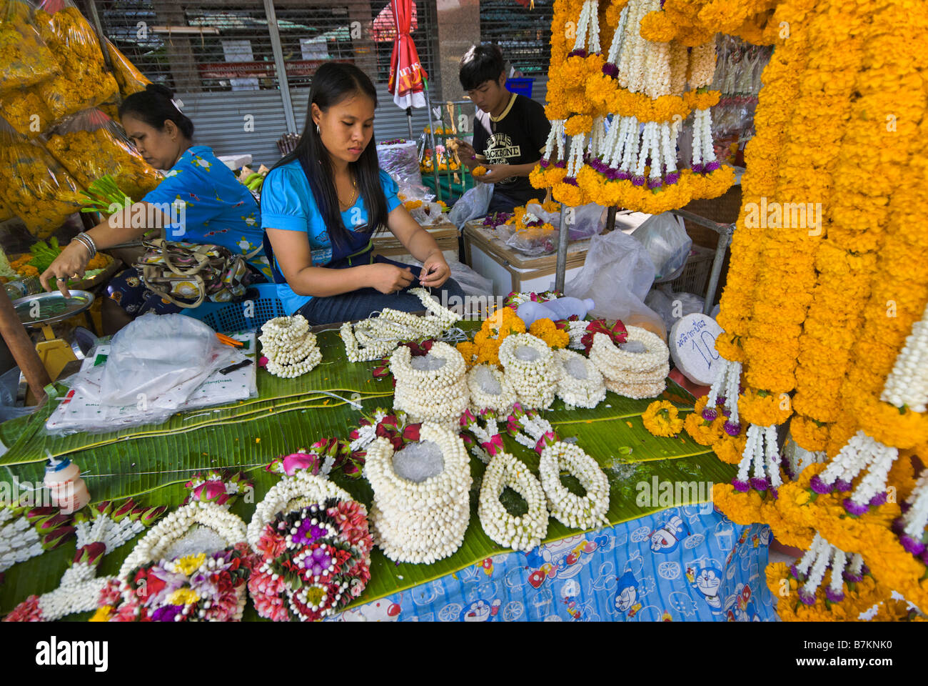 Les femmes thaïlandaises en fleur de dévotion offerts sur un étal au marché aux fleurs de Pak Khlong Talad Bangkok Thaïlande Banque D'Images