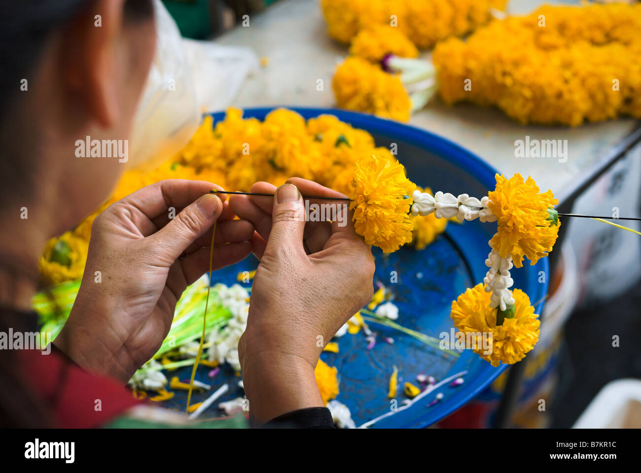 Détail de la femme faisant des offrandes de fleurs de dévotion sur un étal au marché aux fleurs de Pak Khlong Talad Bangkok Thaïlande Banque D'Images