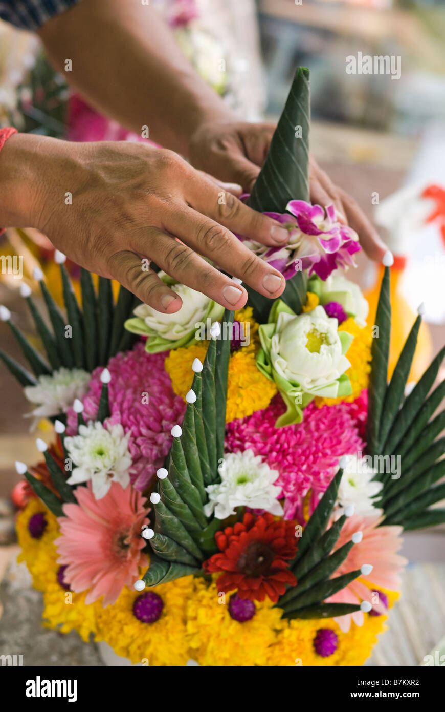 Détail de la personne qui fait l'offre de fleurs de dévotion sur un étal au marché aux fleurs de Pak Khlong Talad Bangkok Thaïlande Banque D'Images