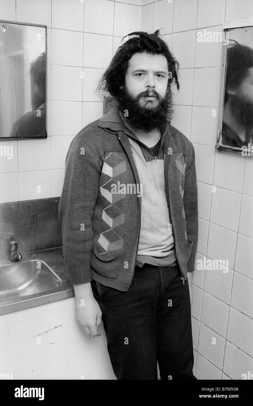 Jeune homme sans-abri avec barbe et cheveux emmêlés en passant la nuit dans une toilette publique pour garder au chaud en hiver UK Banque D'Images Jeune homme sans-abri avec barbe et cheveux emmêlés en passant la nuit dans une toilette publique pour garder au chaud en hiver UK Banque D'Images