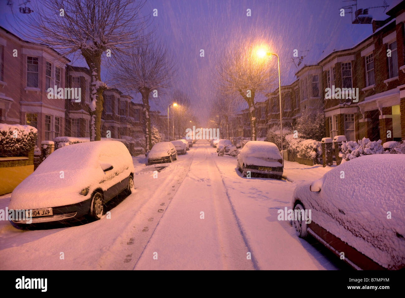 Il neige dans la nuit sur une rue de Londres avec des voitures couvertes Banque D'Images