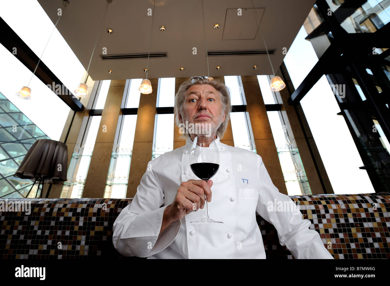 Le chef français Pierre Gagnaire pose avec un verre de vin à son restaurant à Tokyo Banque D'Images