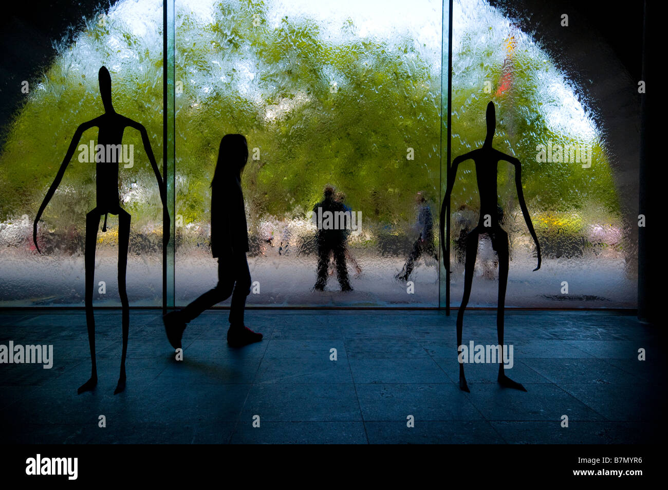 Un visiteur de la National Gallery of Victoria de Melbourne en passant devant la silhouette des sculptures dans le hall de la galerie Banque D'Images