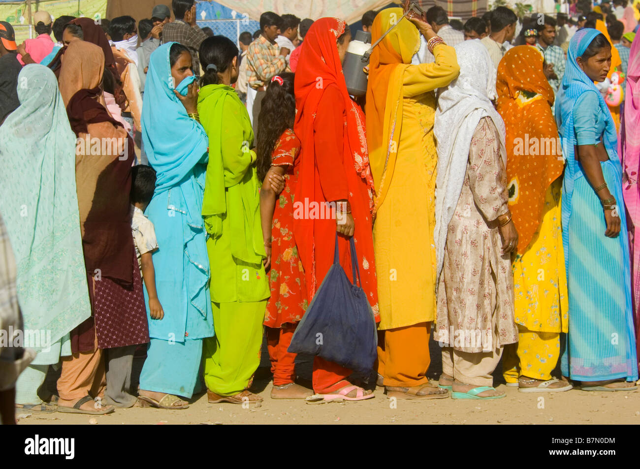 Une longue file d'attente des femmes et des jeunes filles vêtues de leurs plus beaux vêtements attendre patiemment la nourriture gratuite au Mewar festival. Banque D'Images