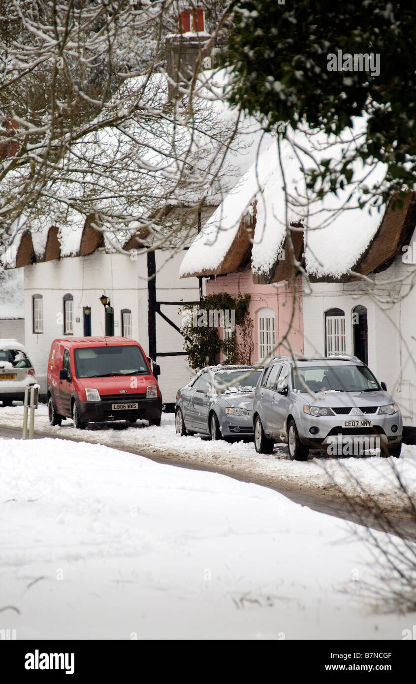 Cottages couverts de neige dans le Hampshire village de Micheldever English hiver neige scène des voitures en stationnement et postmans van Banque D'Images