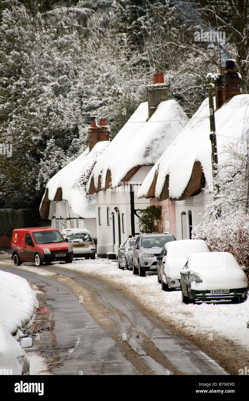 Cottages couverts de neige dans le Hampshire village de Micheldever English hiver neige scène des voitures en stationnement et postmans van Banque D'Images