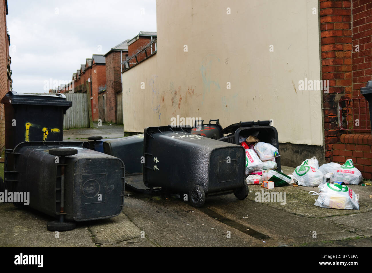 Déchets ménagers bacs/poubelles mensonge déboulonnée sur rue avec contenu éparpillés sur chaussée/trottoir/sentier Banque D'Images