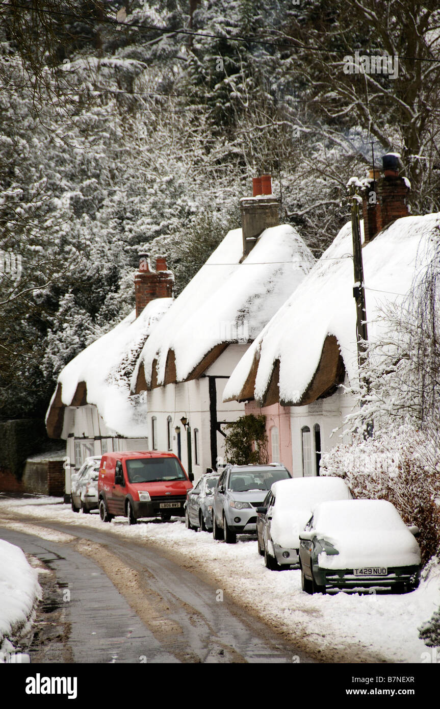 Cottages couverts de neige dans le Hampshire village de Micheldever English hiver neige scène des voitures en stationnement et postmans van Banque D'Images