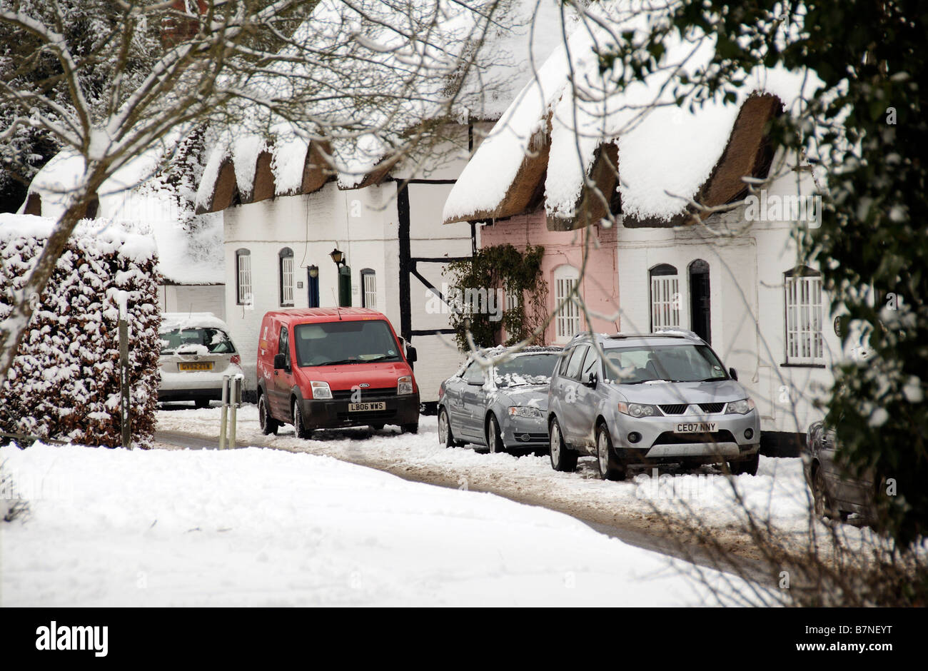 Cottages couverts de neige dans le Hampshire village de Micheldever English hiver neige scène des voitures en stationnement et postmans van Banque D'Images