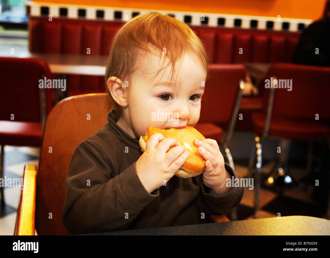 Enfant (15 mois) ancien premier Hamburger jamais manger un hamburger dans un restaurant. Banque D'Images