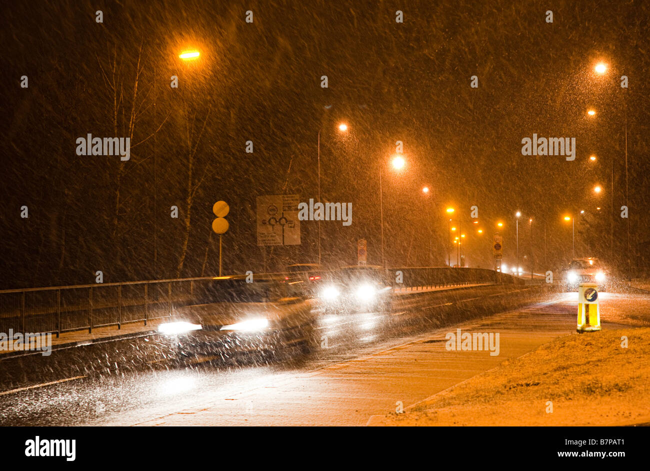 Les voitures qui circulent de nuit dans des conditions de neige hiver Cwmbran Wales UK Banque D'Images Les voitures qui circulent de nuit dans des conditions de neige hiver Cwmbran Wales UK Banque D'Images