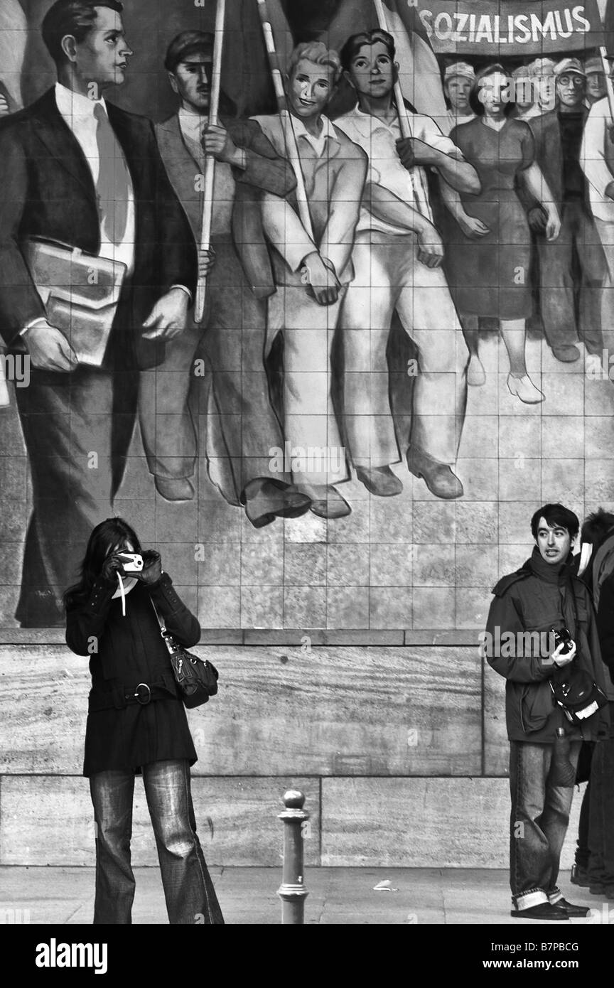 Deux touristes en face d'une peinture murale pour la gloire du socialisme, sur le bâtiment du Ministère de l'air du Reich, l'Allemagne. Banque D'Images
