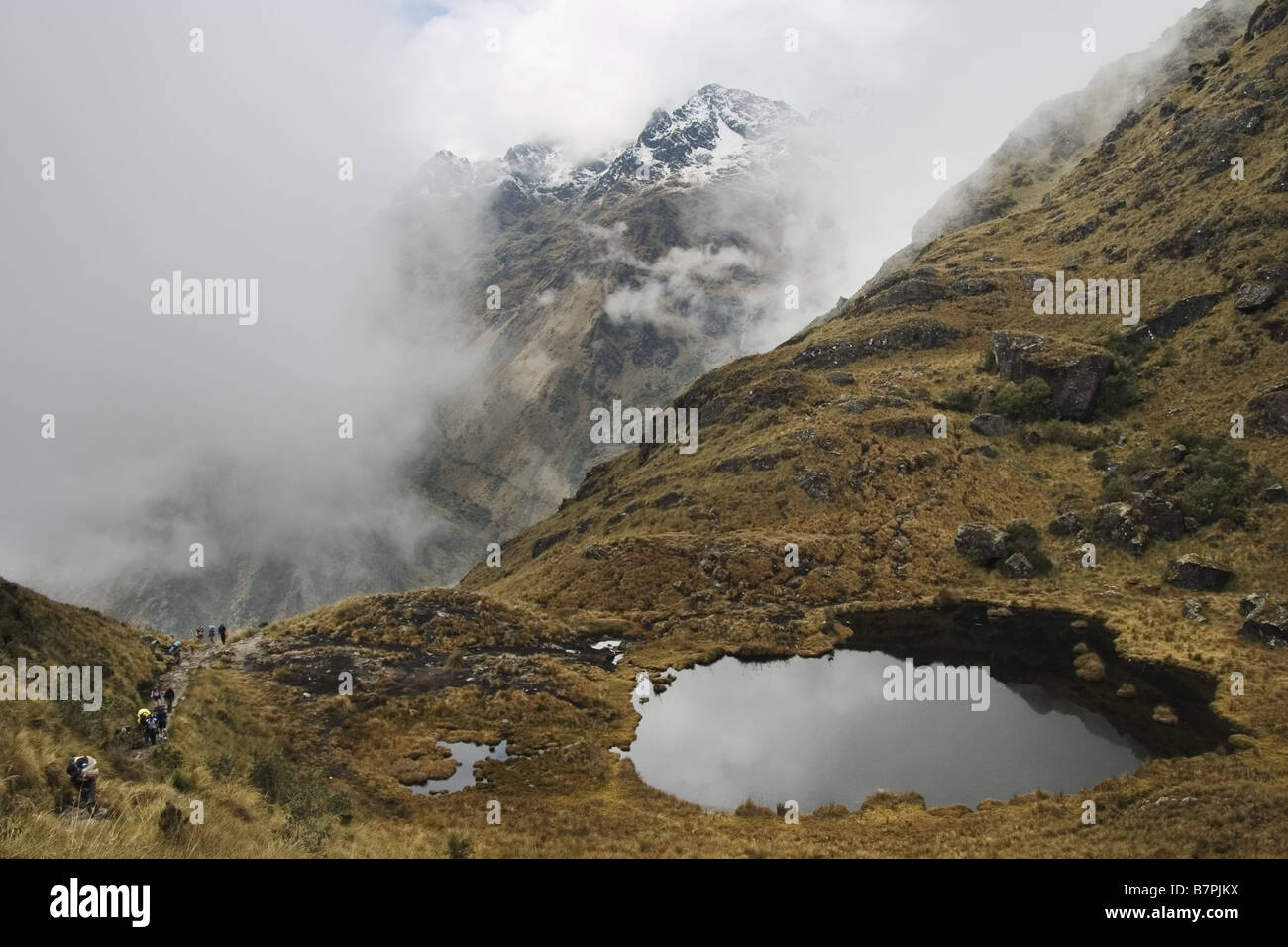 Les randonneurs et les porteurs de la randonnée le sentier des Incas passer un petit lac alpin sur leur voyage au Machu Picchu, au Pérou. Banque D'Images
