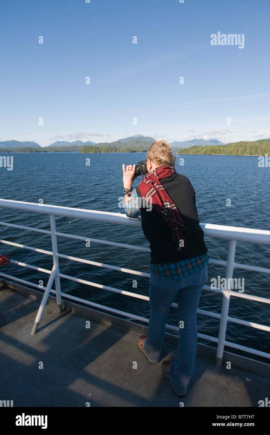 Touriste à prendre des photos avec un appareil photo reflex numérique à partir de la plate-forme arrière du ferry de l'Alaska le long du Passage intérieur Banque D'Images