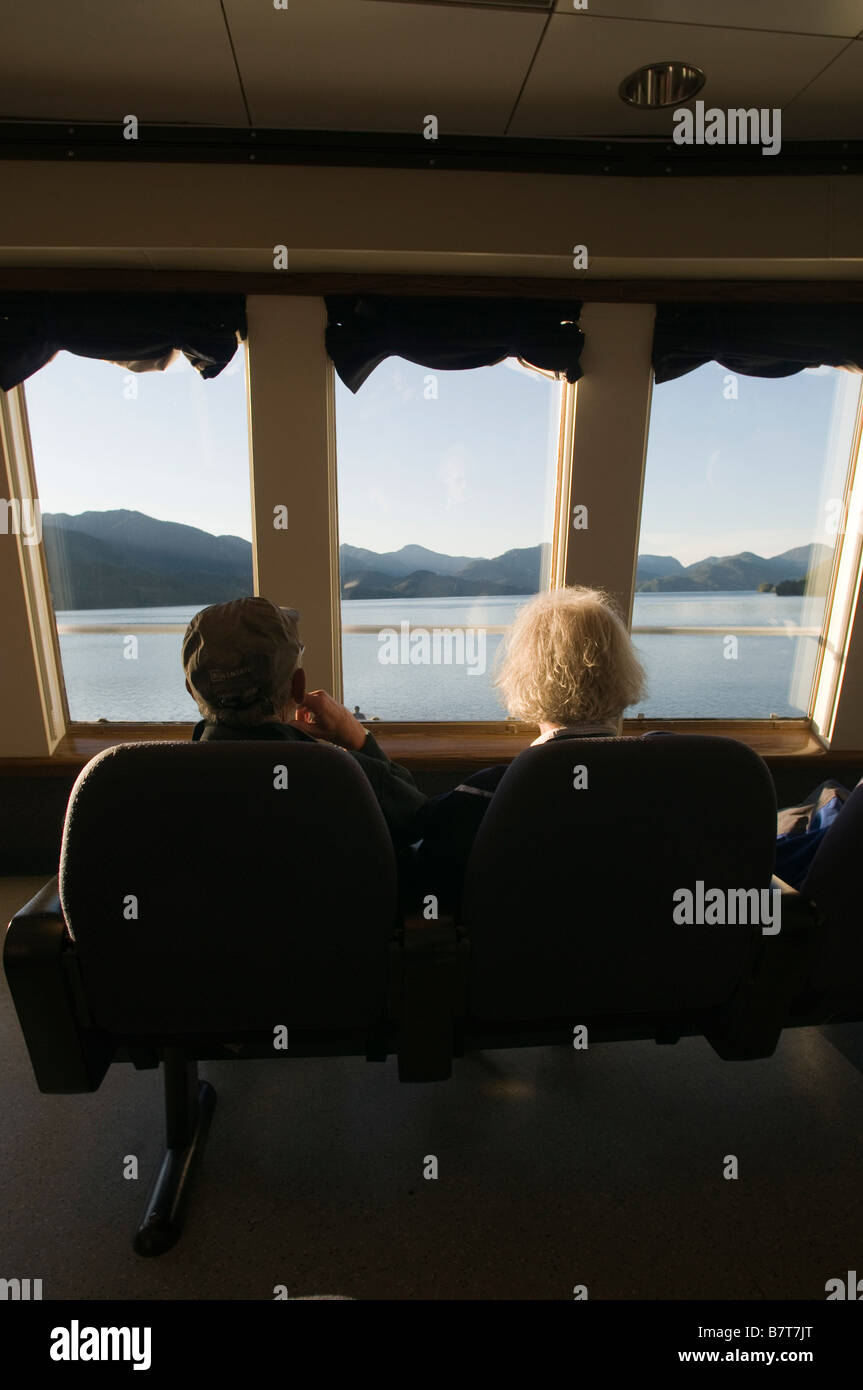 Les touristes à la recherche par la fenêtre de la plate-forme d'observation de l'Alaska Marine Highway le long du Passage intérieur sud-est de l'Alaska Banque D'Images
