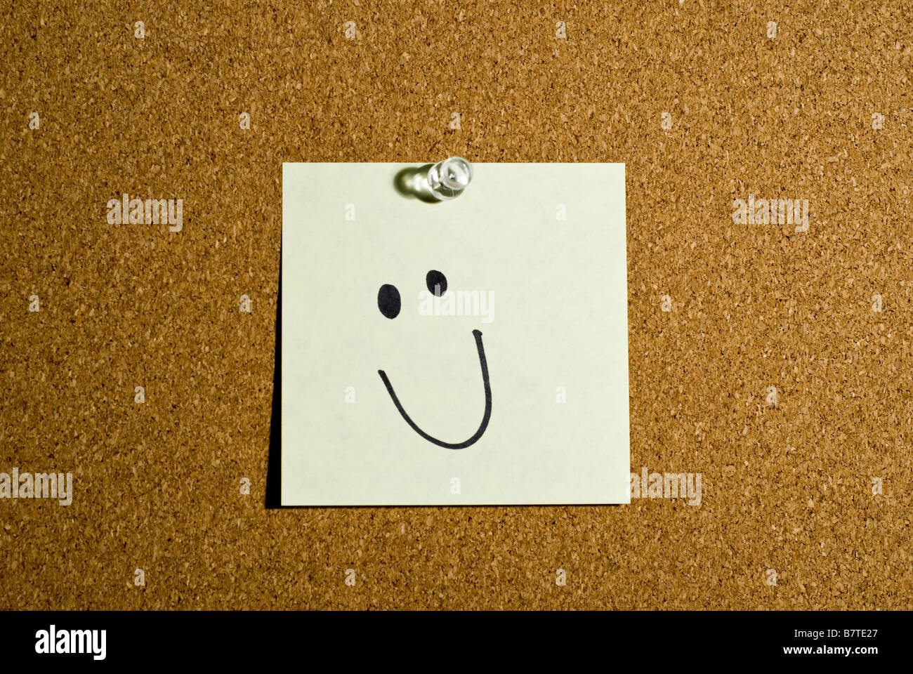 Post-it ou mémo sur un panneau de liège qui a un smiley. Banque D'Images