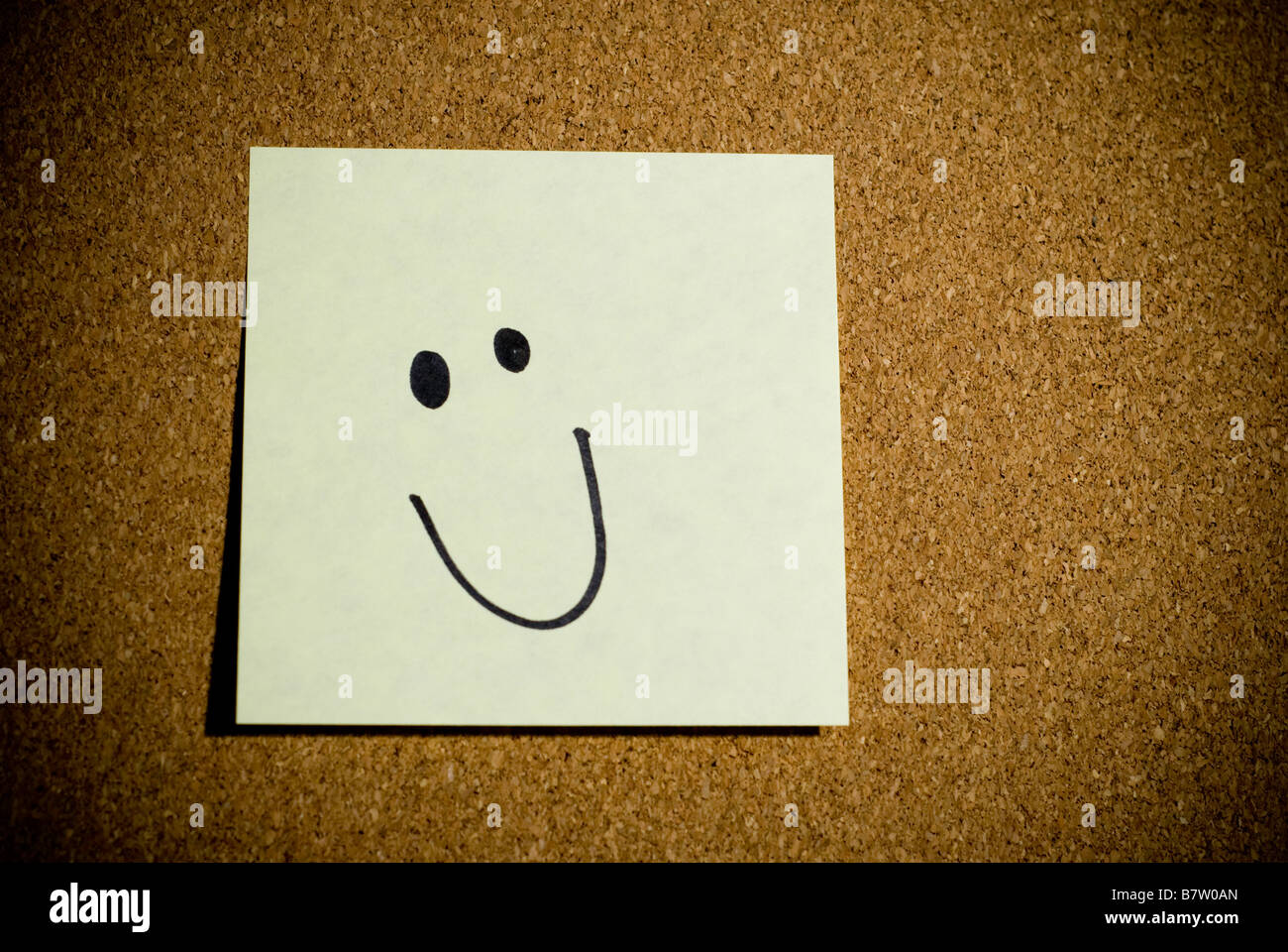Post-it ou mémo sur un panneau de liège qui a un smiley. Banque D'Images