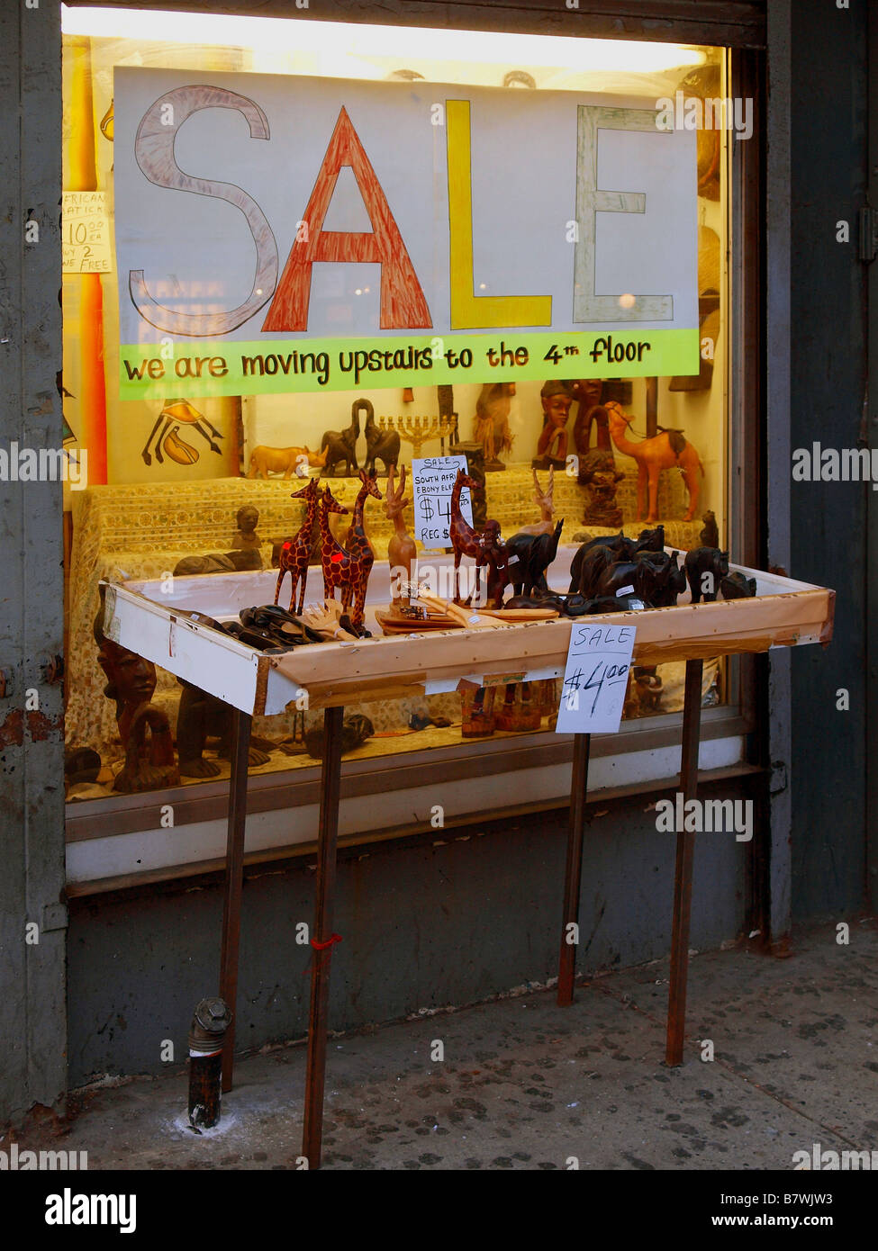 Petit animal statuettes et des chiffres sur la vente sur un tableau d'affichage branlante devant une affiche-fenêtre dessinée à la main dans la ville de New York. Banque D'Images