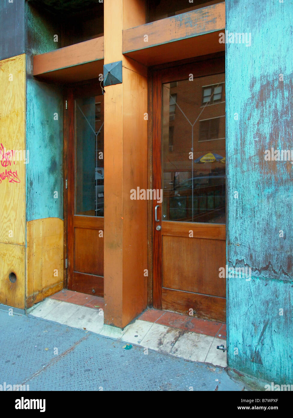 Un ensemble de portes en bois avec des fenêtres en verre sur un bâtiment non utilisé, en cours de rénovation à Manhattan, New York. Banque D'Images