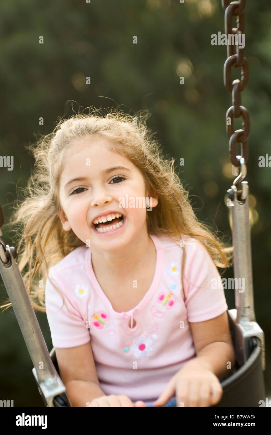 Little girl playing on swing laughing Banque D'Images