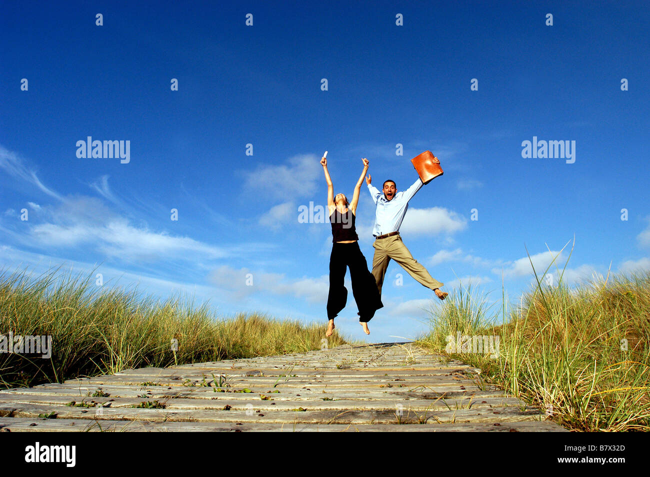 Businessman and businesswoman sauter dans l'air pour célébrer la réussite sur la côte sud-ouest Banque D'Images
